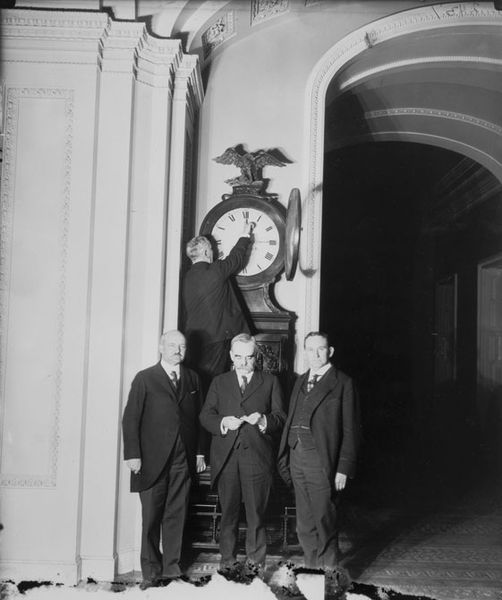 Senate Sergeant at Arms Charles Higgins turns forward the Ohio Clock for the first Daylight Saving Time, while Senators William Calder (NY), William Saulsbury, Jr. (DE), and Joseph T. Robinson (AR) look on, 1918. Photo Credit: Senate Historical Office
