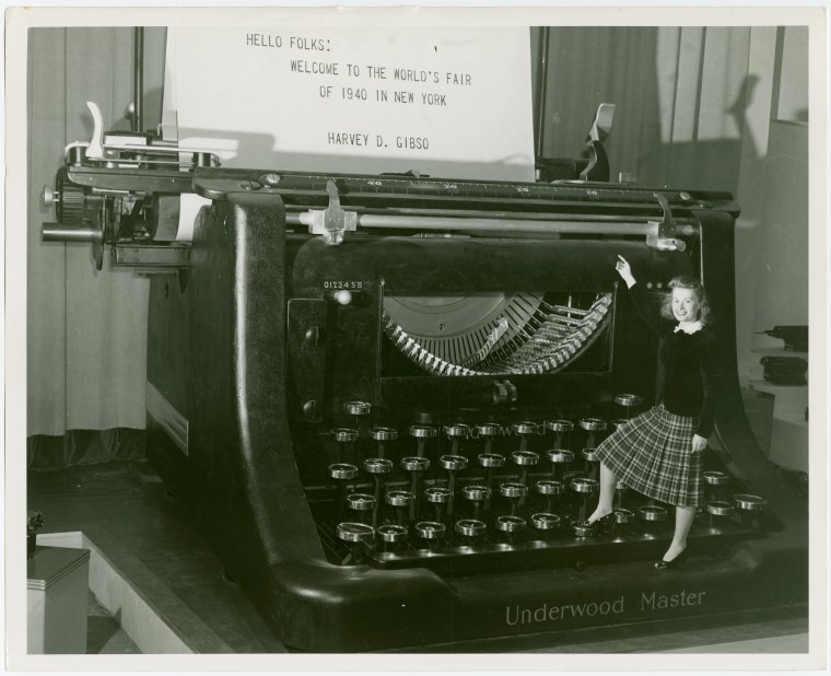 With her right foot poised on the “N” key, pretty Miss Muriel Davis is about to complete a message of greeting from Harvey D. Gibson, chairman of the board of the World’s Fair of 1940 in New York to visitors to the big exposition. Photo Credit: New York Public Library