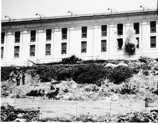 Smoke, possibly from a grenade, pours from a window of the Alcatraz cellhouse. The wall is pockmarked with bullet holes fired by officers in an attempt to subdue the loose convicts during the Battle of Alcatraz. (History By Zim) Smoke, possibly from a grenade, pours from a window of the Alcatraz cellhouse. The wall is pockmarked with bullet holes fired by officers in an attempt to subdue the loose convicts during the Battle of Alcatraz. (History By Zim)
