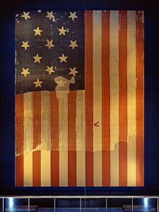 The large Star Spangled Banner Flag that inspired the lyrics of the US national anthem when it flew above Fort McHenry in the 1814 Battle of Baltimore. Shown here on display at the Smithsonian's National Museum of History and Technology, around 1964. Many pieces were cut off the flag and given away as souvenirs early during its history. A linen backing, attached in 1914, shows the original extent of the flag.